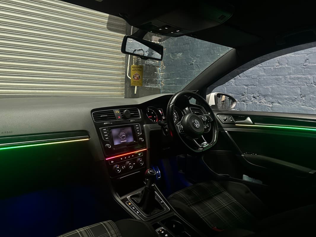 Green ambient lighting along the dashboard and doors of a VW Golf GTI