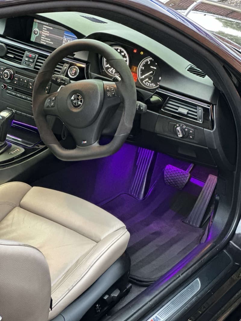 Purple footwell lighting in a BMW cabin, from the driver's door