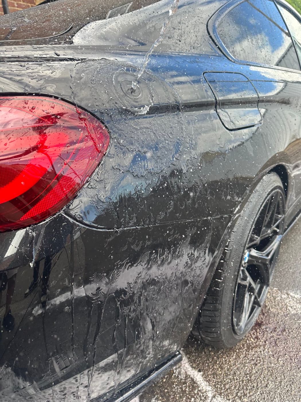 A black BMW covered in dirt and foam before being washed