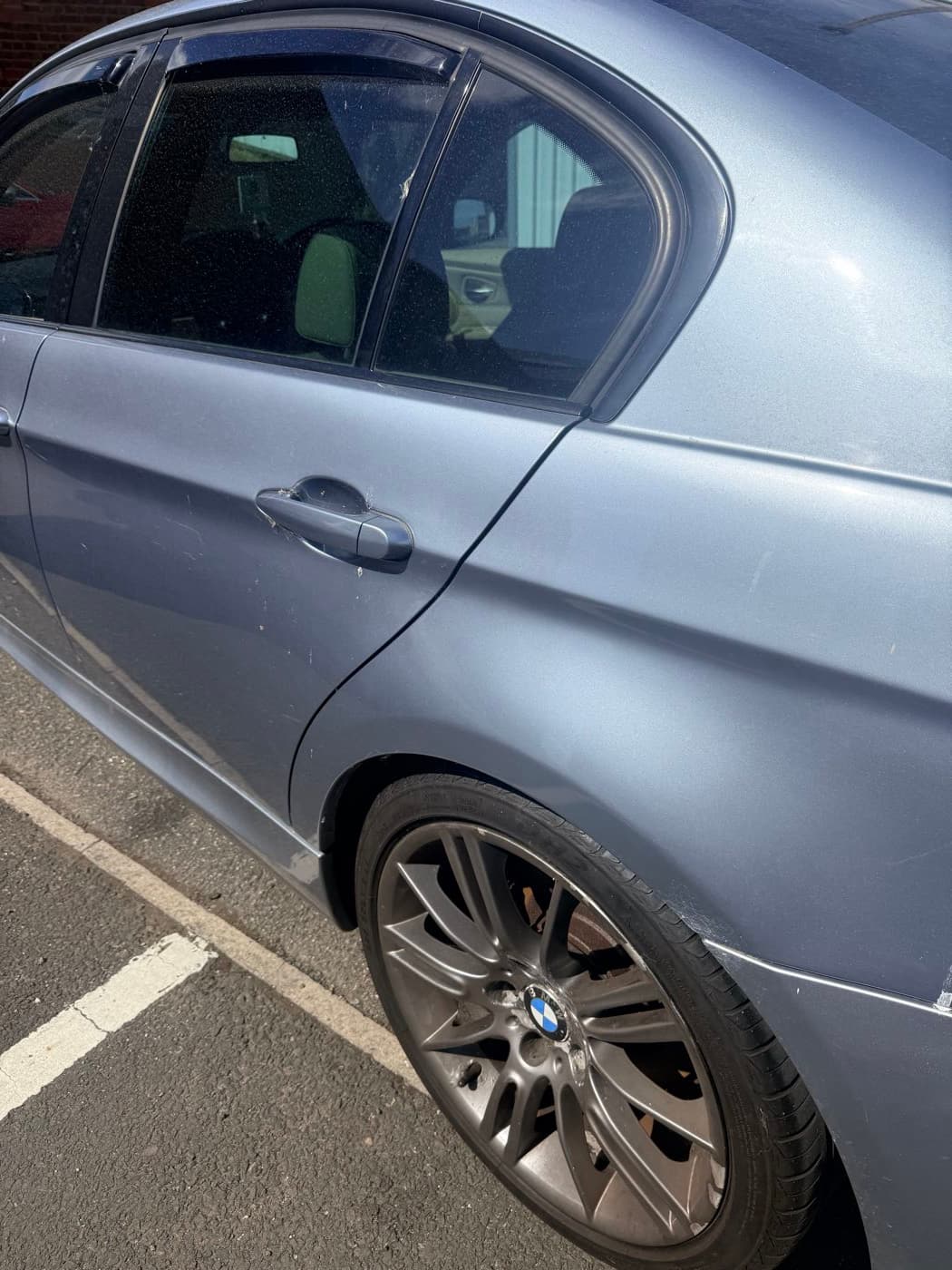 A silver BMW 3 Series dirty, with brake dust across the wheel