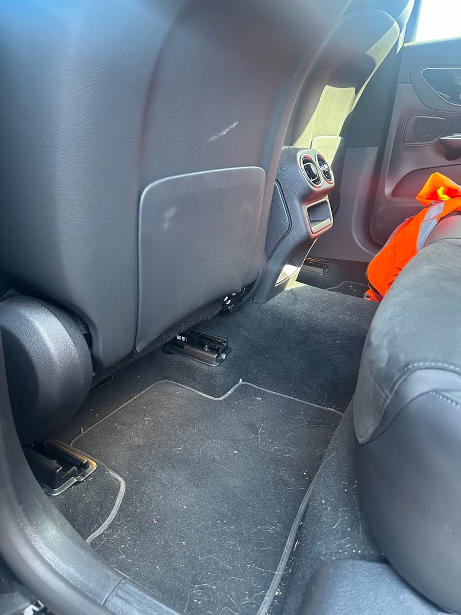 A rear footwell before valeting, mats covered in dirt and lint