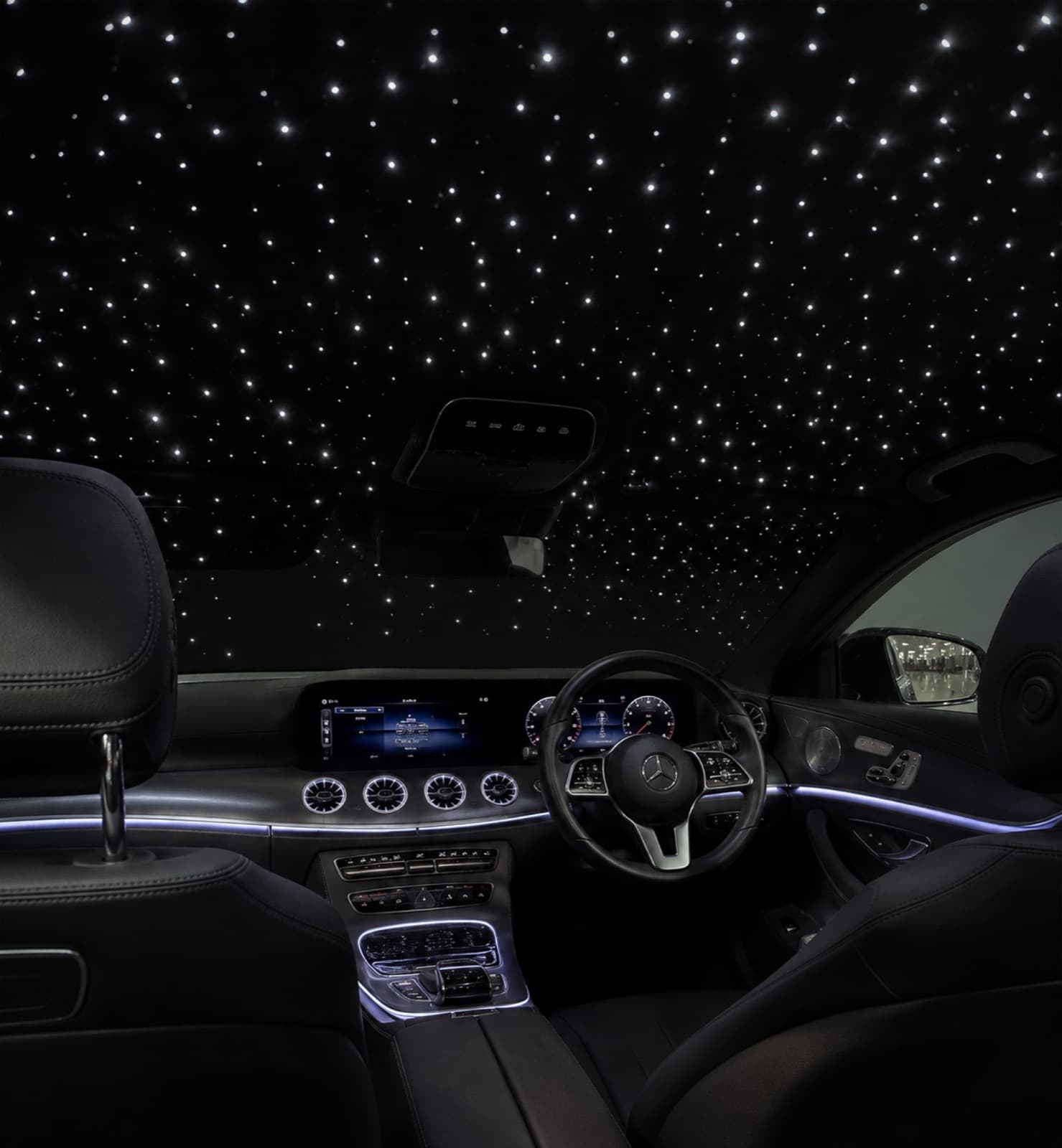 Starlight headliner glowing above a car's front seats