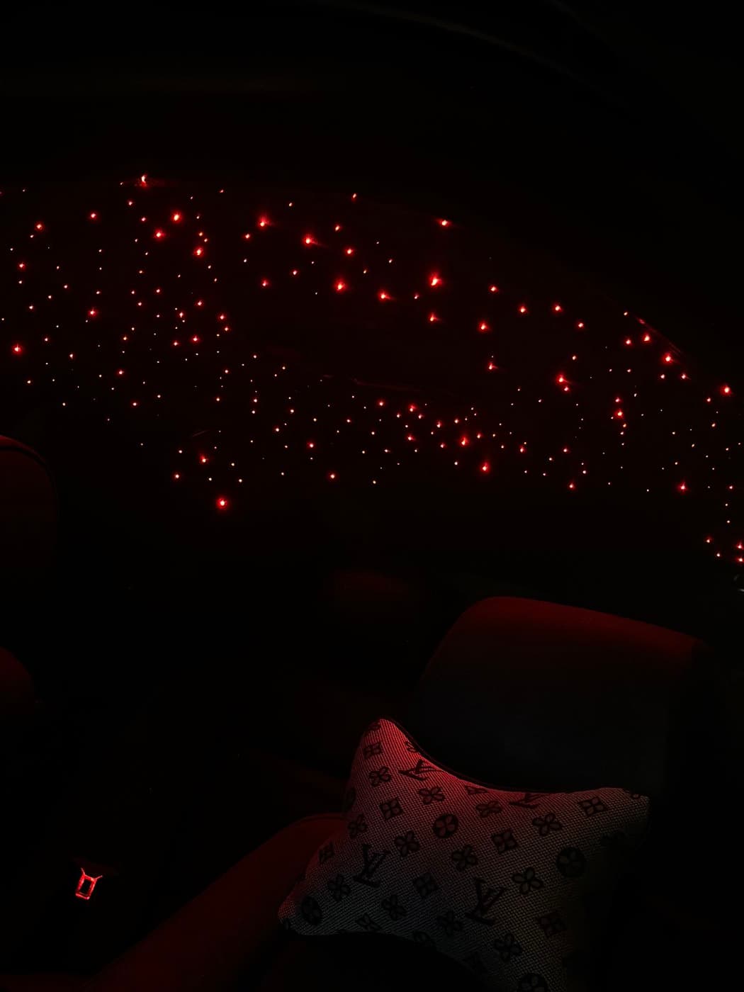 Red starlight headliner glowing above the rear seats at night