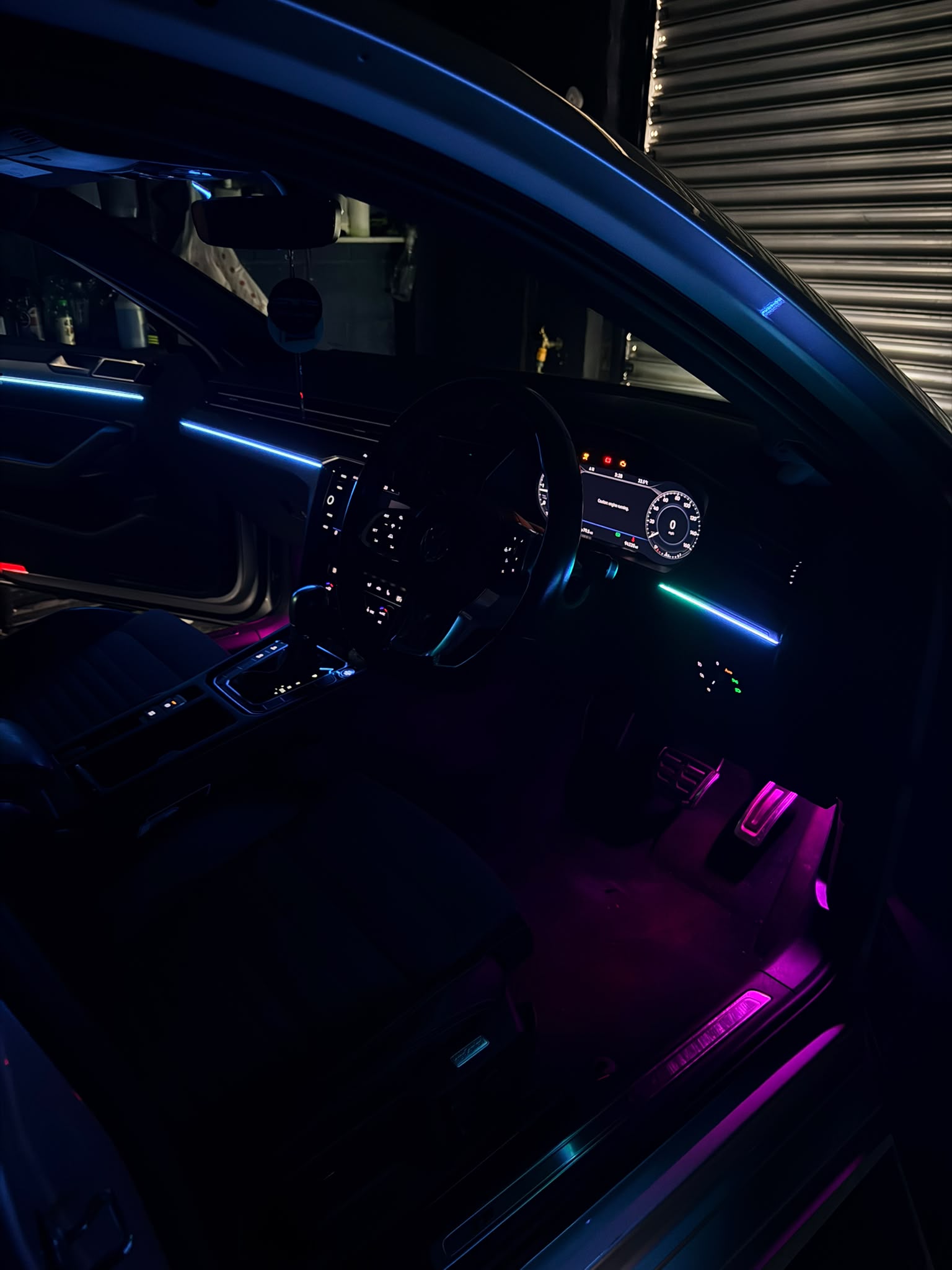 Cyan ambient strip across the dashboard with the steering wheel lit